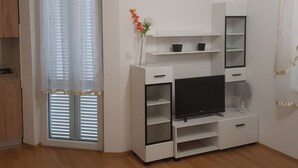 Una sala de estar moderna con un televisor de pantalla plana, estanterías empotradas y una mesita de noche con lámpara.