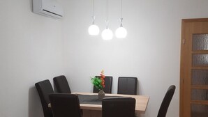 Un comedor con una mesa de madera, sillas negras y tres lámparas colgantes.