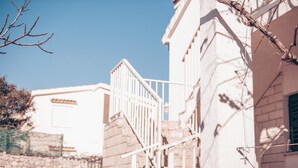 Un escalier menant à un bâtiment doté d’une façade en pierre et d’une balustrade blanche.