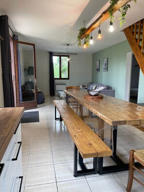 Un comedor moderno con una mesa de madera, bancos e lámparas colgantes.