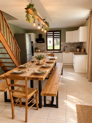 Un comedor con una mesa de madera preparada para seis personas, un banco y una escalera.