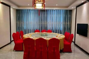 Un salón de conferencias con una mesa redonda, sillas rojas y un telón de fondo azul.