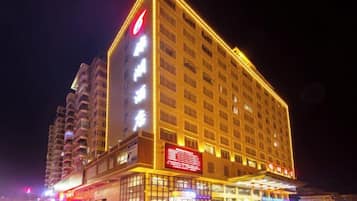 A multi-story hotel with illuminated signage and a prominent red logo on the facade.