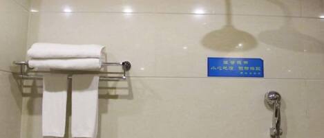 A bathroom with a shower, a towel rack with towels, and a sign with text.