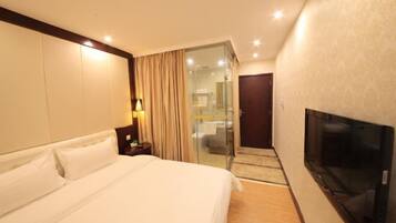 A hotel room with a large bed, a television, and a sliding door leading to a bathroom.