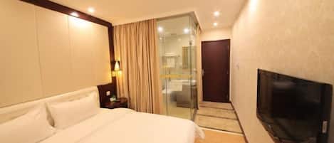 A hotel room with a large bed, a television, and a sliding door leading to a bathroom.