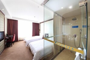 A hotel room with two beds, a desk with a chair, a TV, and a glass-enclosed shower area. - Kumho Hotel (Wengyuan)