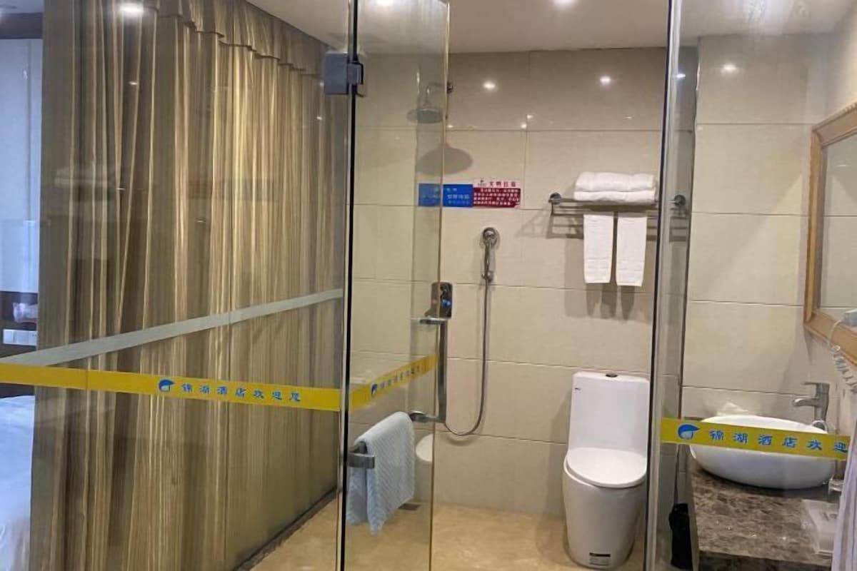 A glass-enclosed shower area with a toilet and sink, a towel rack, and a sign indicating a private room.