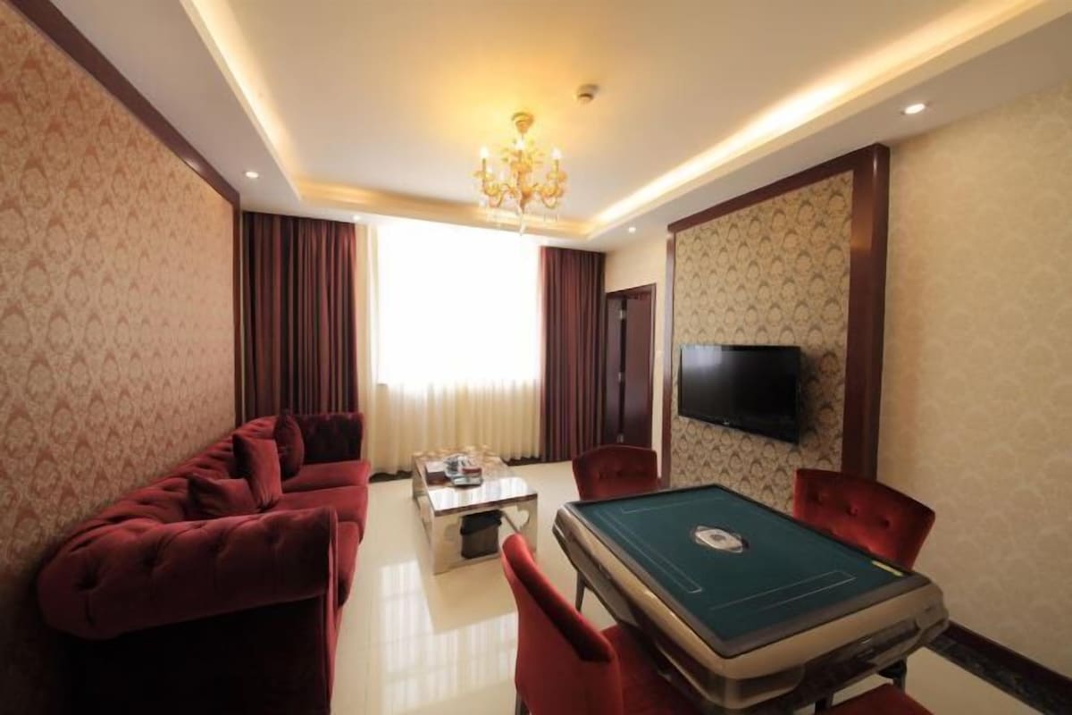 A room with a pool table, red upholstered sofa, and a television mounted on the wall.