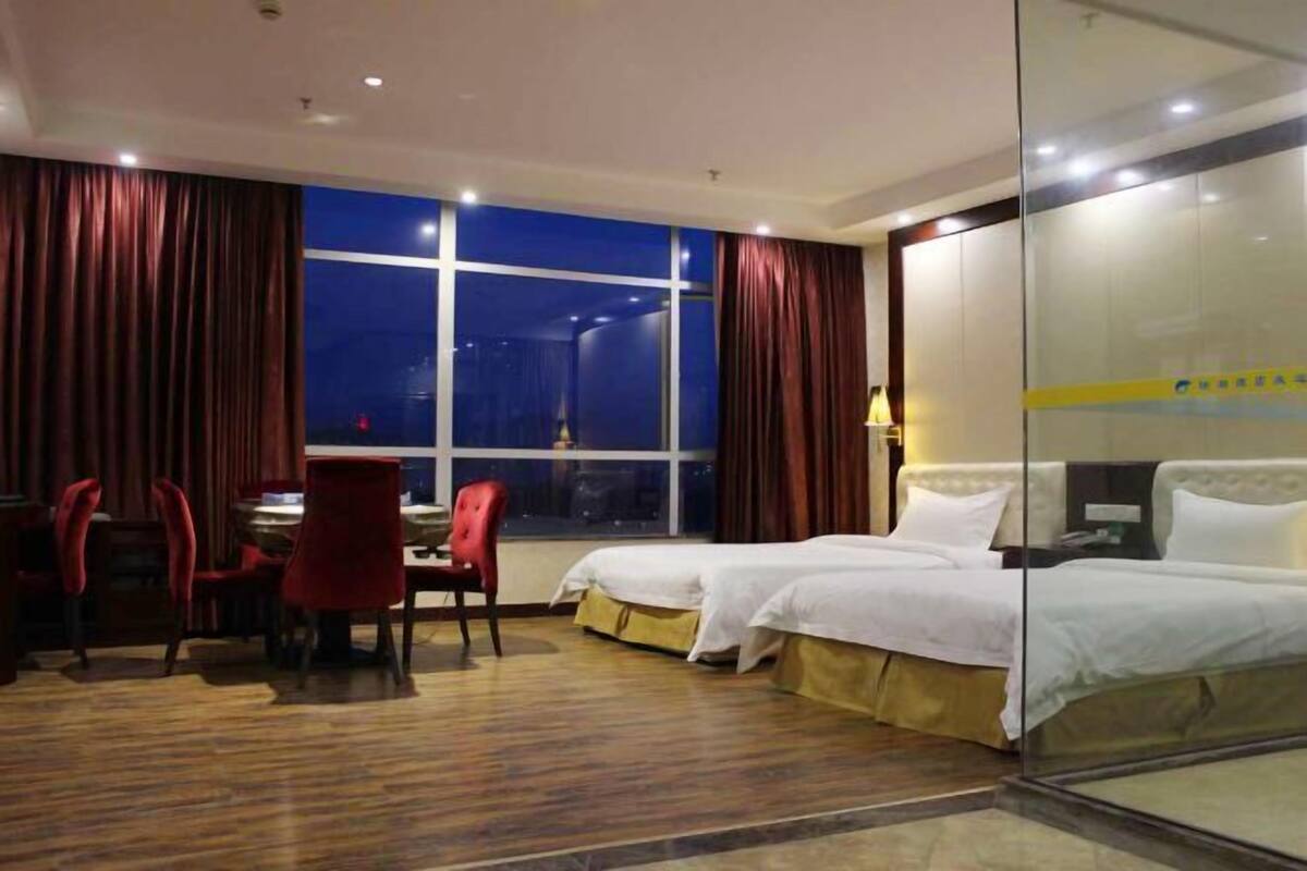 A hotel room with two beds, a desk, and a chair.