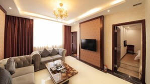 A modern living room with a sofa set, a coffee table, a flat-screen TV, and a chandelier. - Kumho Hotel (Wengyuan)
