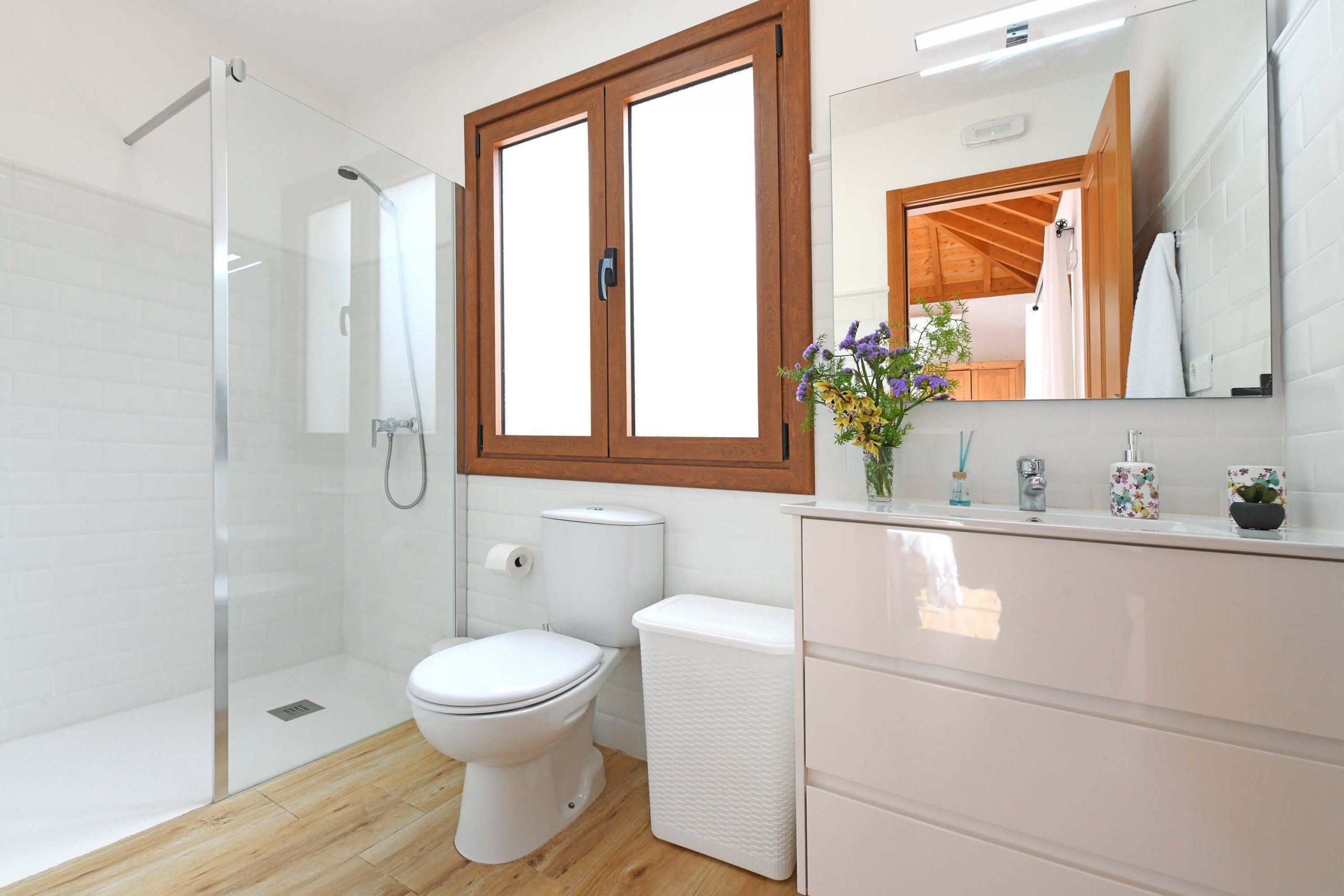Une salle de bain moderne avec une douche à parois de verre, des toilettes et un meuble-lavabo avec un miroir.