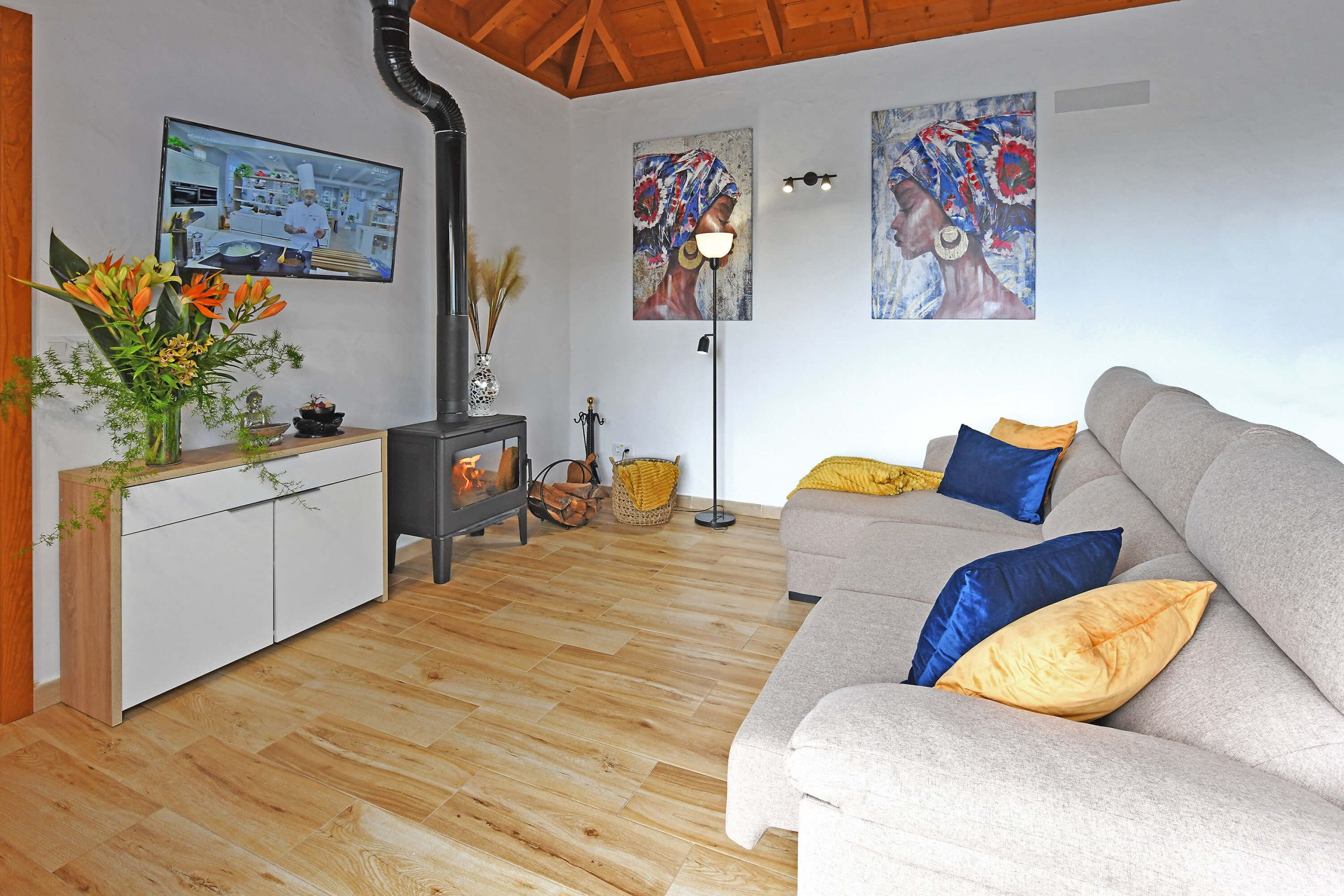 Una sala de estar moderna con un sofá, un televisor, una chimenea y obras de arte en las paredes.