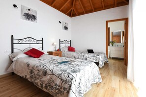 A bedroom with two beds, wooden flooring, and a wooden ceiling.