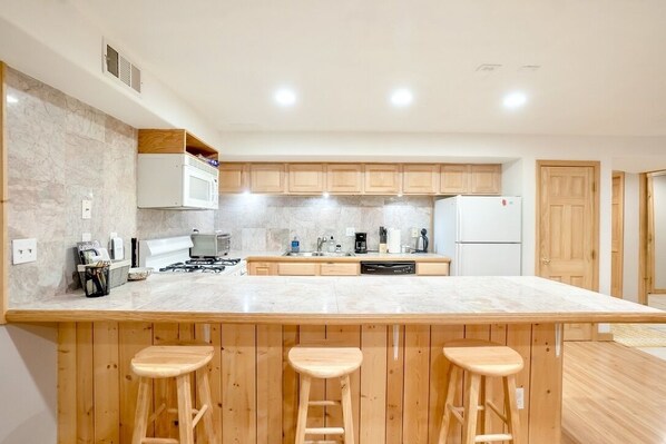 A modern kitchen with a large island, wooden bar stools, and built-in appliances.