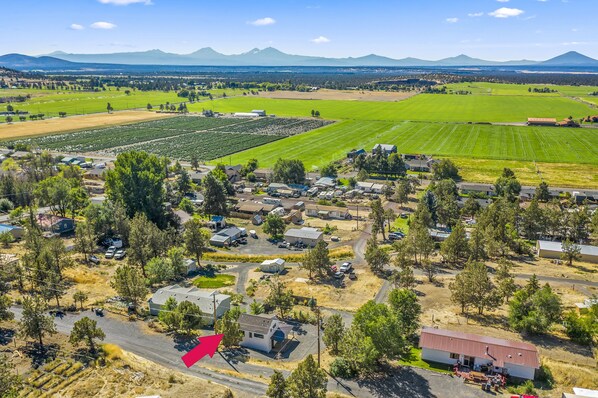 Zona rural con casas, campos y una cadena montañosa al fondo.