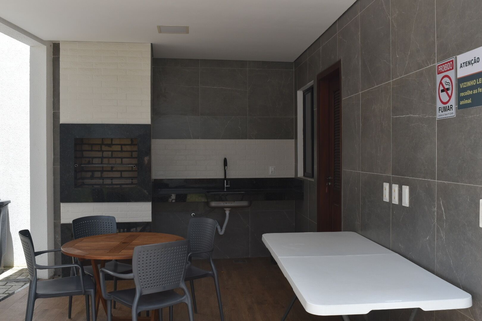 A modern kitchen with a built-in grill, a dining area with a table and chairs, and a white countertop.