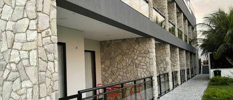 Un edificio moderno con fachada de piedra, un área de estar al aire libre techada y un camino pavimentado.