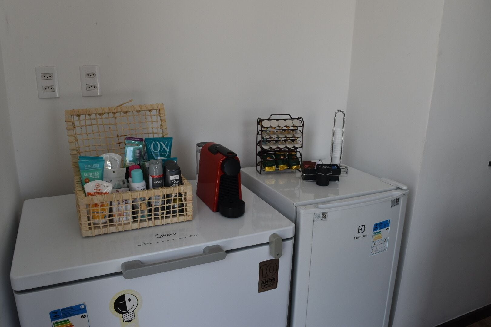 Una kitchenette compacta con refrigerador, microondas y un lavamanos pequeño.