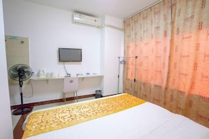 A hotel room with a bed, a desk, a chair, a TV, and a window with curtains. - Haikou Jinmeng Hotel (Haikou)