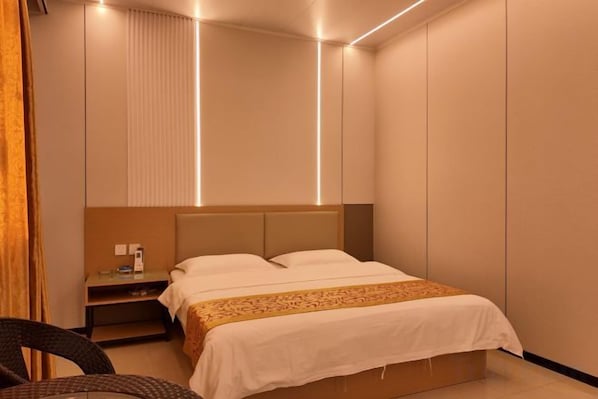 A modern hotel room with a bed, bedside table, and a chair. - Haikou Jinmeng Hotel (Haikou)