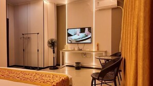 A hotel room with a bed, a desk, a chair, a television, and a wardrobe. - Haikou Jinmeng Hotel (Haikou)