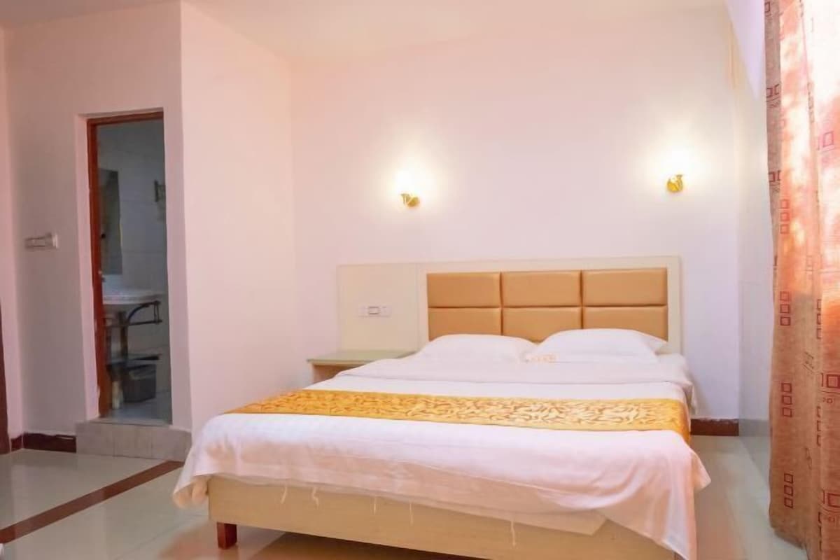 A hotel room with a bed, a nightstand, and two wall-mounted lights.