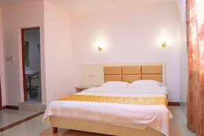 A hotel room with a bed, a nightstand, and two wall-mounted lights. - Haikou Jinmeng Hotel (Haikou)