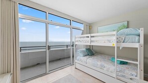 Una stanza con un letto a castello, un'ampia porta-finestra scorrevole che dà su un balcone e un quadro appeso al muro.