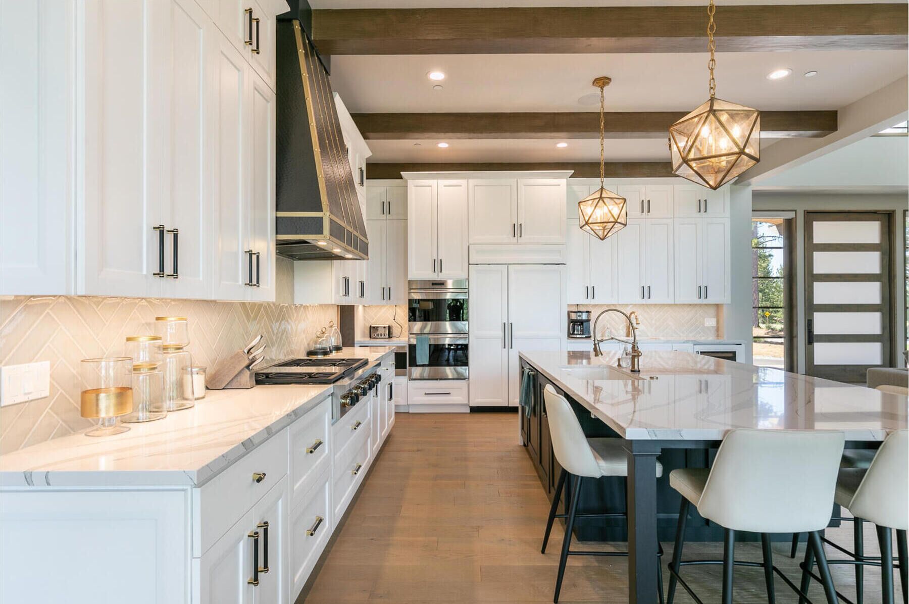 Una cocina moderna con armarios blancos, una isla central e iluminación colgante.