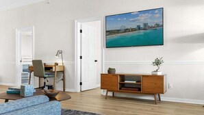 A living room with a sofa, coffee table, TV, and a cityscape view. - Spacious 4BR Beach House w/ Pool | Pura Vida (North Myrtle Beach)