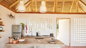 A kitchen with a central island, a refrigerator, and a wall-mounted light fixture. - Pacific SurfShack Ocean View Mal Pais/Santa Teresa (Santa teresa)