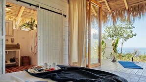 A bedroom with a large bed, a book, a tray with food, and a view of the ocean. - Pacific SurfShack Ocean View Mal Pais/Santa Teresa (Santa teresa)