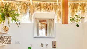 A bathroom with a wooden vanity, a mirror, a towel rack, a green plant, and a blue stool. - Pacific SurfShack Ocean View Mal Pais/Santa Teresa (Santa teresa)