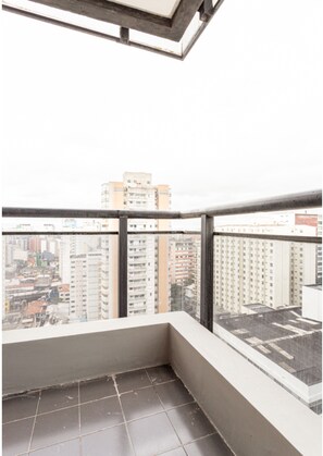 Een balkon met betegelde vloer en uitzicht op de stad.