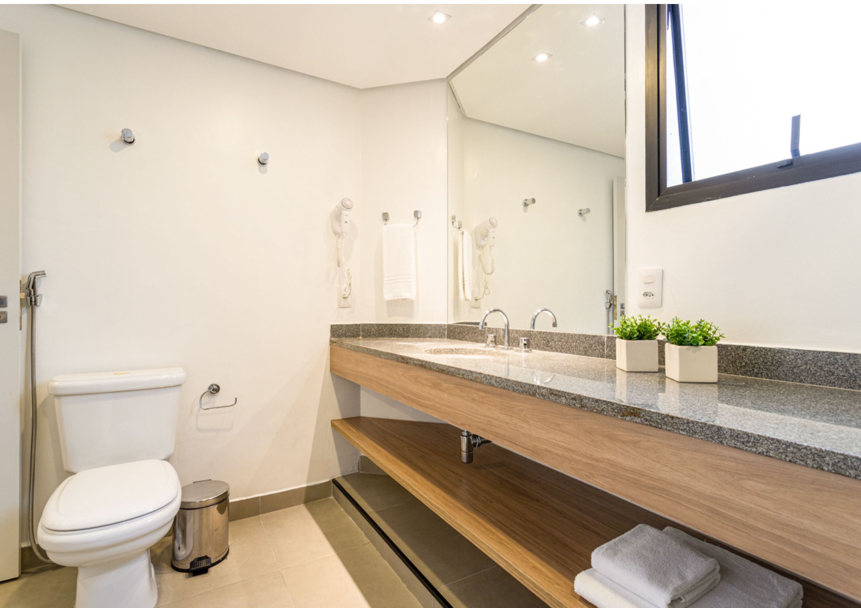A modern bathroom with a toilet, bidet, sink, and mirror.