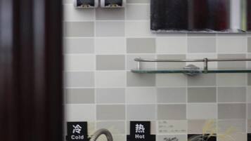A bathroom with a tiled wall, a towel rack, and a shelf.