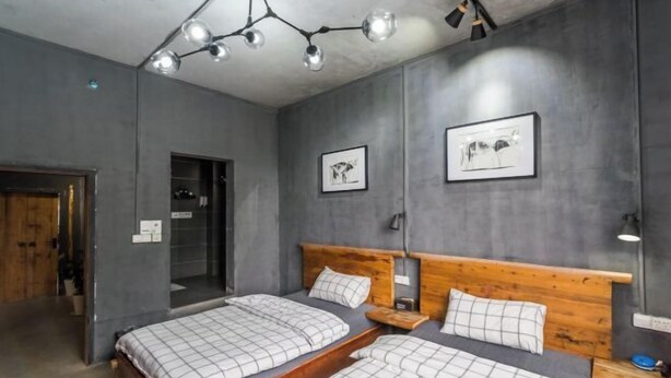 Ein Schlafzimmer mit zwei Betten, Holz-Kopfteilen und einer Deckenleuchte.