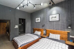 Une chambre avec deux lits, des têtes de lit en bois et un luminaire fixé au plafond.