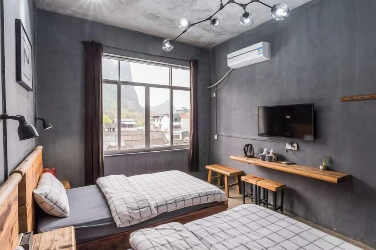 A room with two beds, a TV, a desk, and a window with a view.