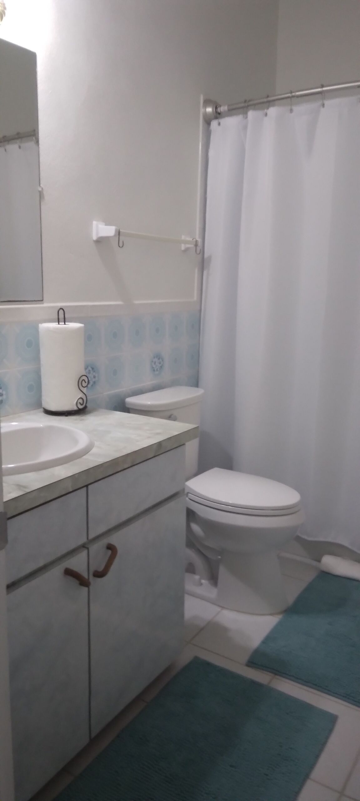 Et badeværelse med toilet, håndvask og bøjlestang til håndklæder.