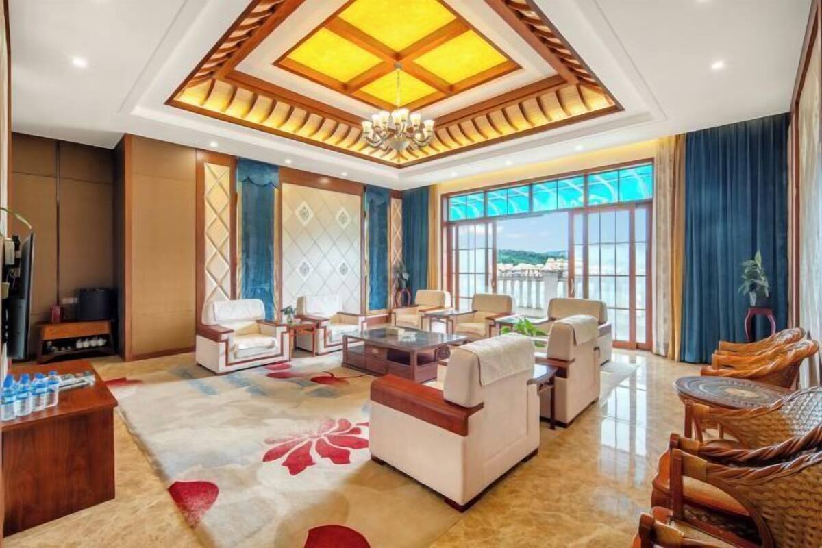 A spacious living room with a large window, a chandelier, and a variety of seating options.