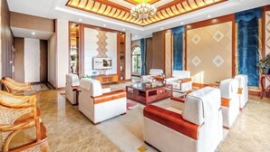 A spacious living room with a high ceiling, a central coffee table, and seating arrangements. - Menluo Wa Jing Luxury Grand Hotel(Hulu Town Wa Tribe Branch) (Cangyuan)