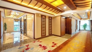Un vestíbulo de hotel con piso de mármol pulido, vigas de madera en el techo y una alfombra estampada con motivos florales.