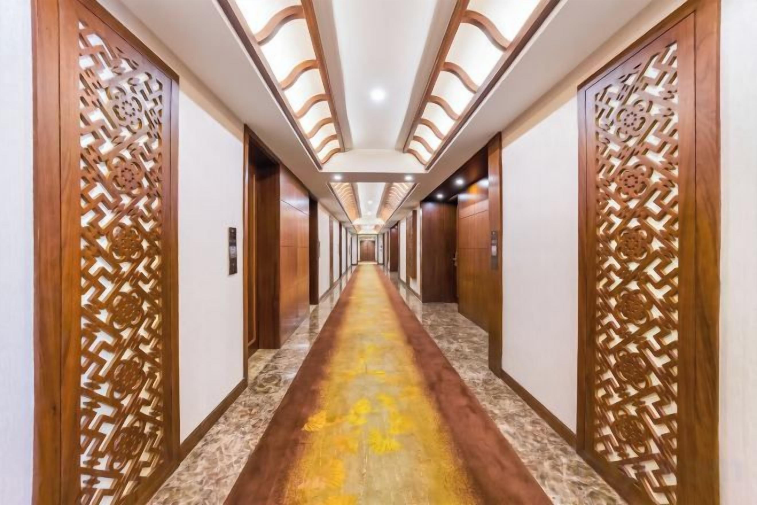 A hotel corridor with wooden paneling, a marble floor, and a long hallway leading to doors.