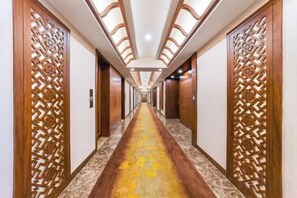 A hotel corridor with wooden paneling, a marble floor, and a long hallway leading to doors. - Menluo Wa Jing Luxury Grand Hotel(Hulu Town Wa Tribe Branch) (Cangyuan)