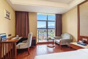 Habitación de hotel con cama, escritorio, silla, una mesita y balcón con vistas.