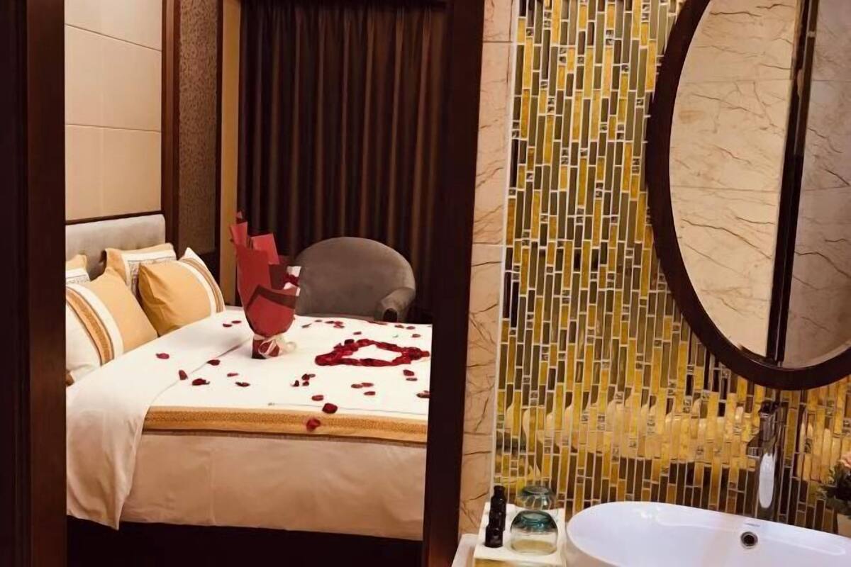 Ein Hotelzimmer mit Bett, einem Sessel, einem Badezimmer mit Waschbecken und einer dekorativen Wand.