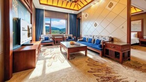 A spacious living room with a sofa set, a coffee table, and a television. - Menluo Wa Jing Luxury Grand Hotel(Hulu Town Wa Tribe Branch) (Cangyuan)