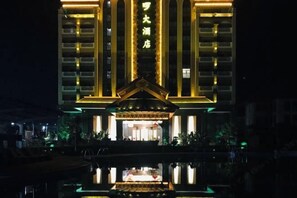 Un hotel con una entrada destacada y su reflejo en el agua.